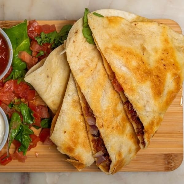 Breakfast Club quesadillas with salsa, sour cream, and fresh greens on a wooden board.