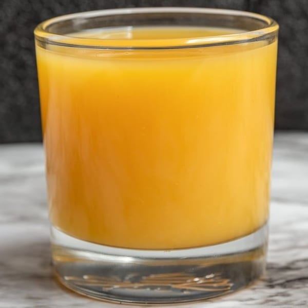 A glass of bright orange juice, a refreshing breakfast drink from Breakfast Club.