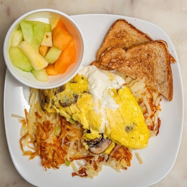 Breakfast Club's omelet with hash browns, toast, and a side of fresh fruit.